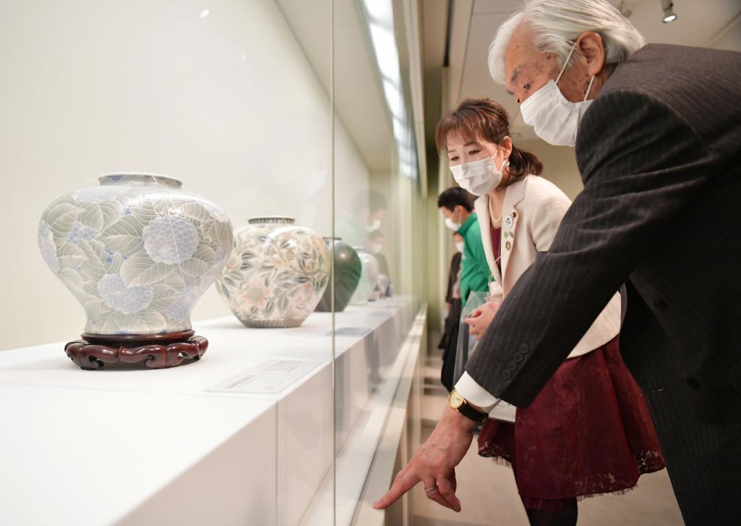 展覧会での公開が107年ぶりとされる「彩磁紫陽花模様花瓶」を見る孫の板谷駿一さん(右)=15日、筑西市丙のしもだて美術館