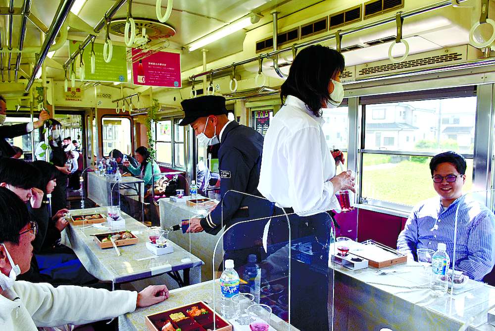 下妻駅行きの列車内で境町醸造ワインを楽しむ乗客たち=常総市内