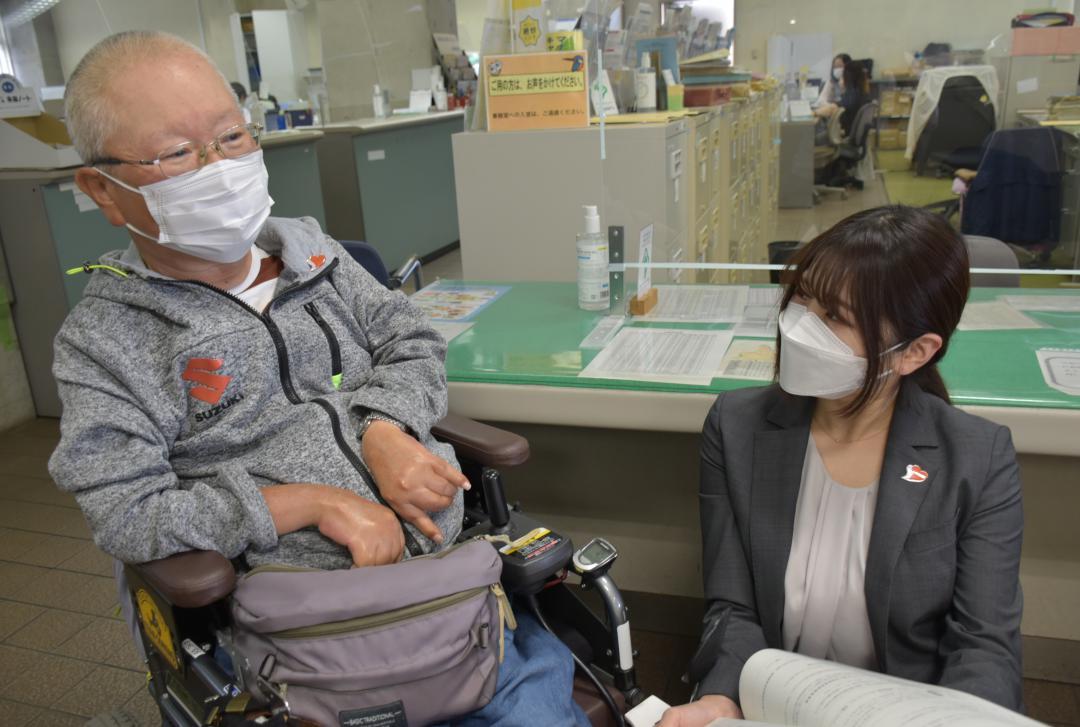 とりで障害者協働支援ネットワーク代表の染野和成さん(左)と話す市担当者。襟には「あいサポートバッジ」=取手市役所
