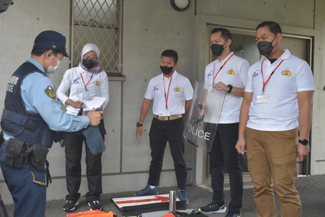 パトカーに積んでいる資機材の説明を受けるインドネシア警察の若手幹部たち=水戸駅南口交番
