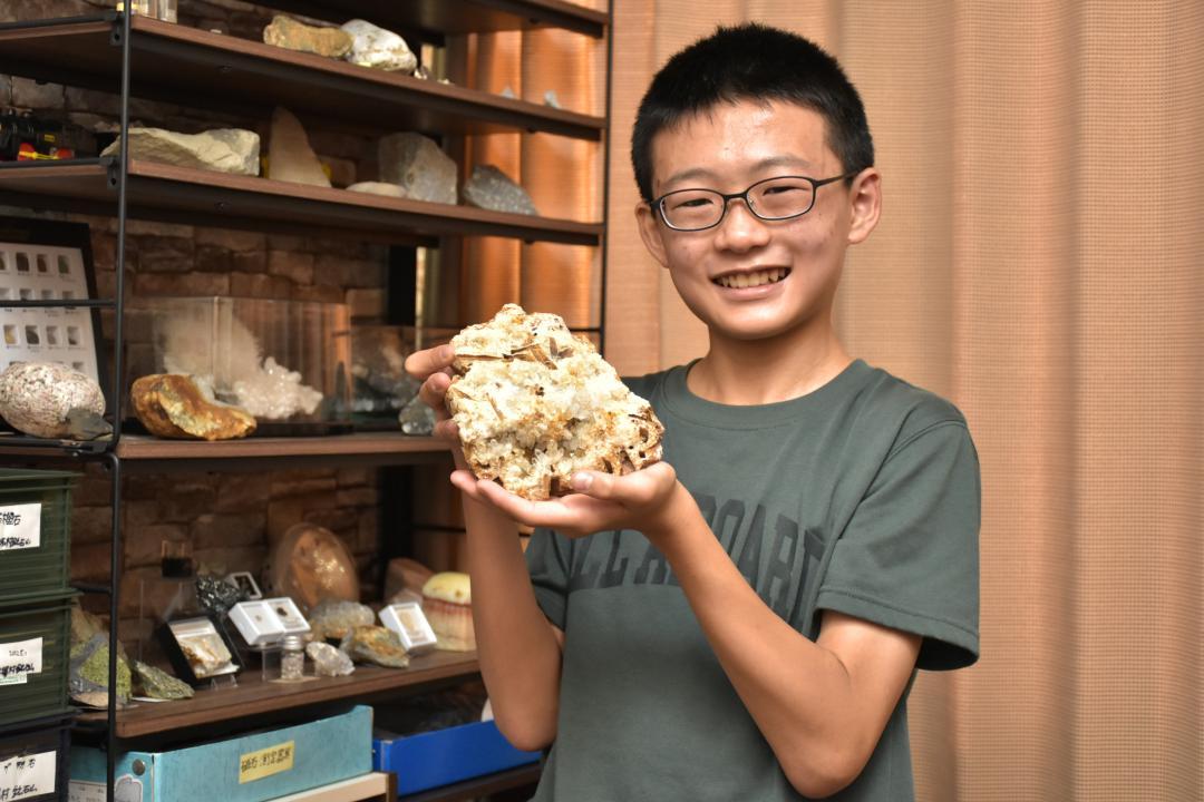自慢のコレクションの一つ、荒川鉱山(秋田県)の水晶を手に笑顔の島本奏汰さん=古河市大山