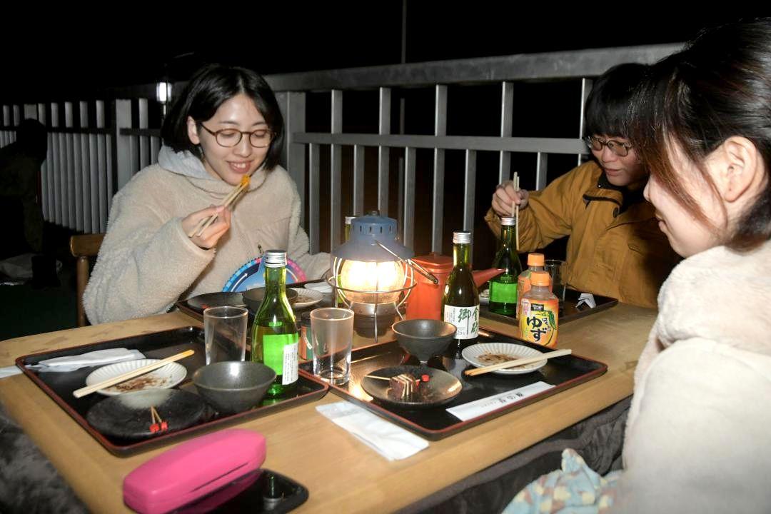 夜の竜神大吊橋で料理を楽しむ「コタツで星空鑑賞会」の参加者=常陸太田市天下野町
