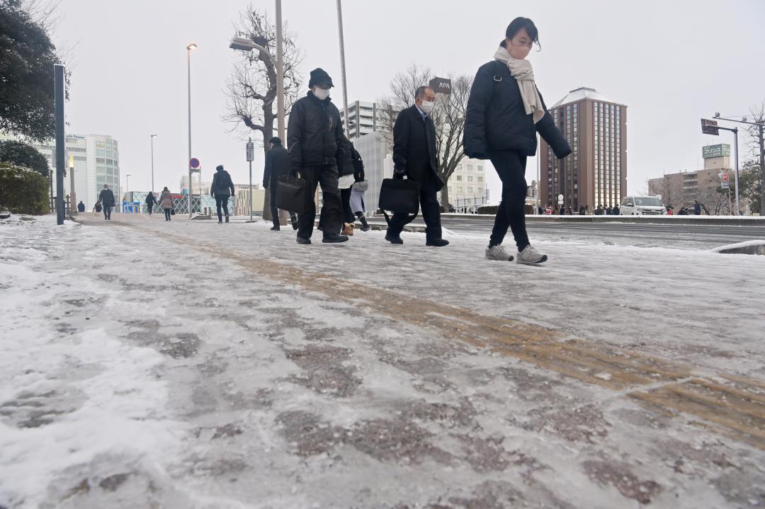 降雪から一夜明け、凍結した路面に気をつけながら通勤する人たち＝25日午前７時57分、水戸市城南