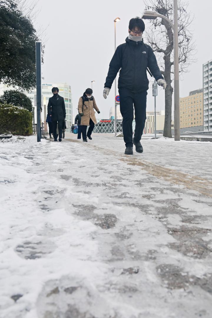 降雪から一夜明け、凍結した路面に気をつけながら通勤する人たち＝25日午前７時29分、水戸市城南