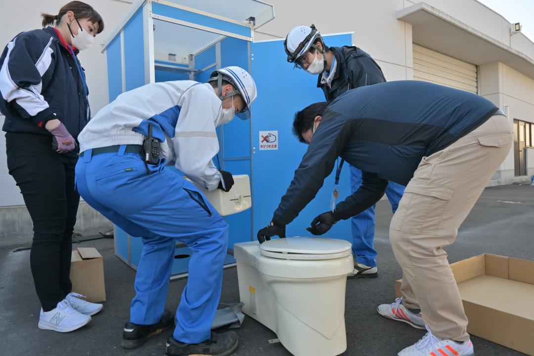 マンホールトイレを設置する職員ら=日立市東成沢町
