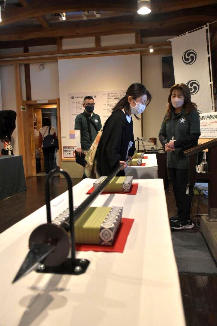 長さ4メートル、重さ22・5キロある「御手杵の槍」を模した重りを持ち上げる来館者=結城市結城