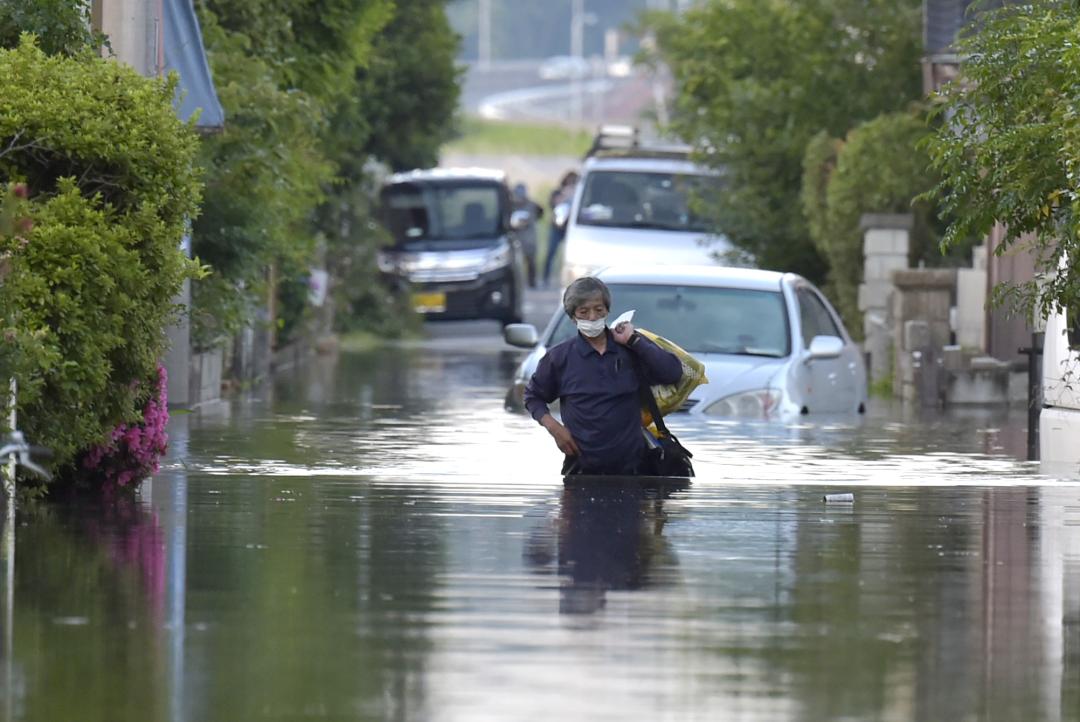 浸水した住宅街を腰まで水に浸かりながら歩く男性=3日午後6時14分、取手市双葉