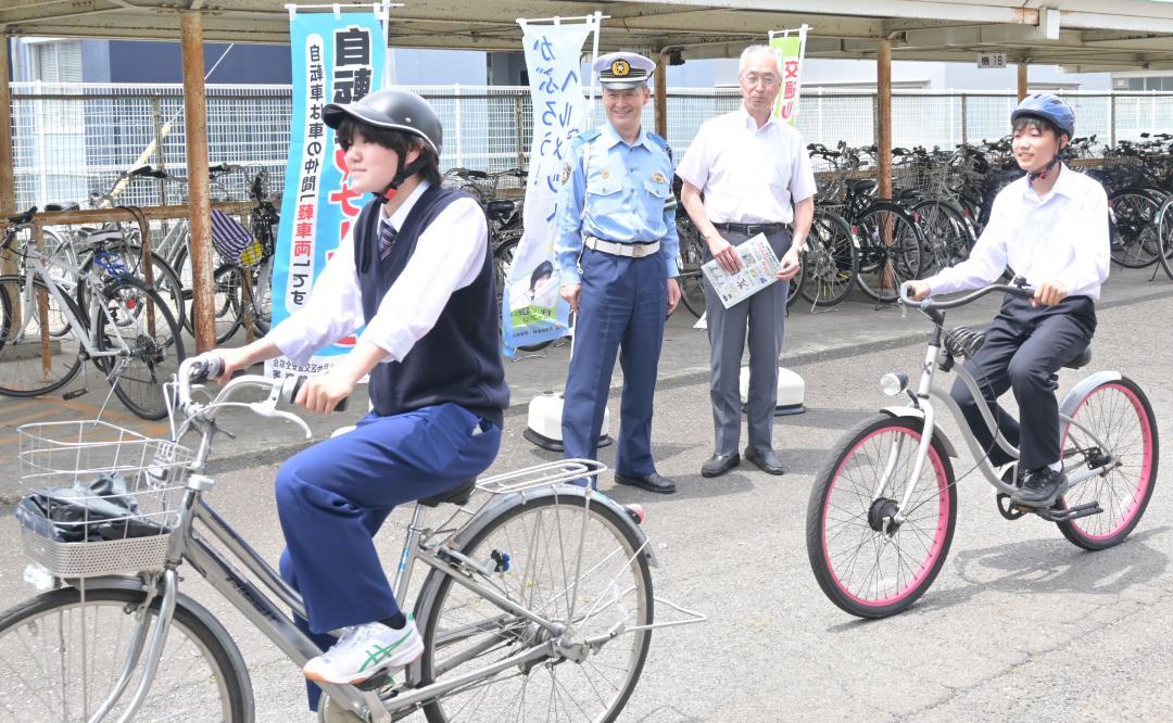 ヘルメットを着用した生徒の自転車走行を見守る、青柳信明署長(後列左)と勝田滋校長(同右)=水戸市元吉田町
