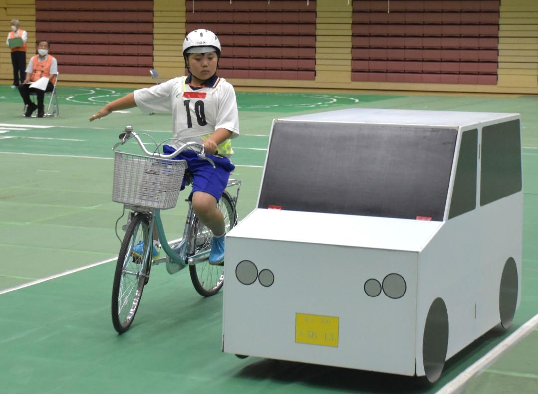 手信号を出しながら駐車車両の脇を通過する児童=ひたちなか市新光町