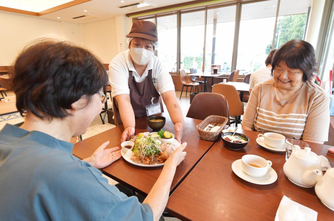 野菜を中心としたランチプレートを提供する接客スタッフ=東海村須和間

