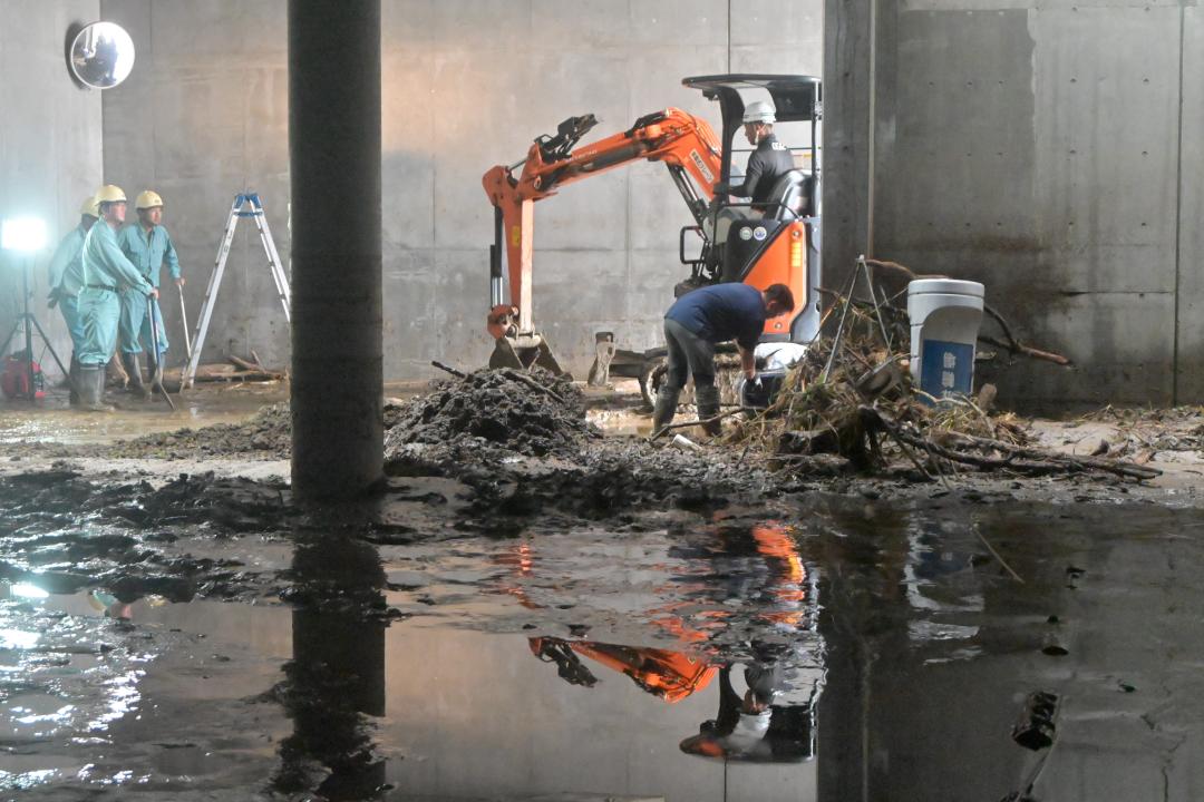 浸水被害で停電した日立市役所地下1階で泥を除去する作業員=9日午後1時15分ごろ、同市助川町