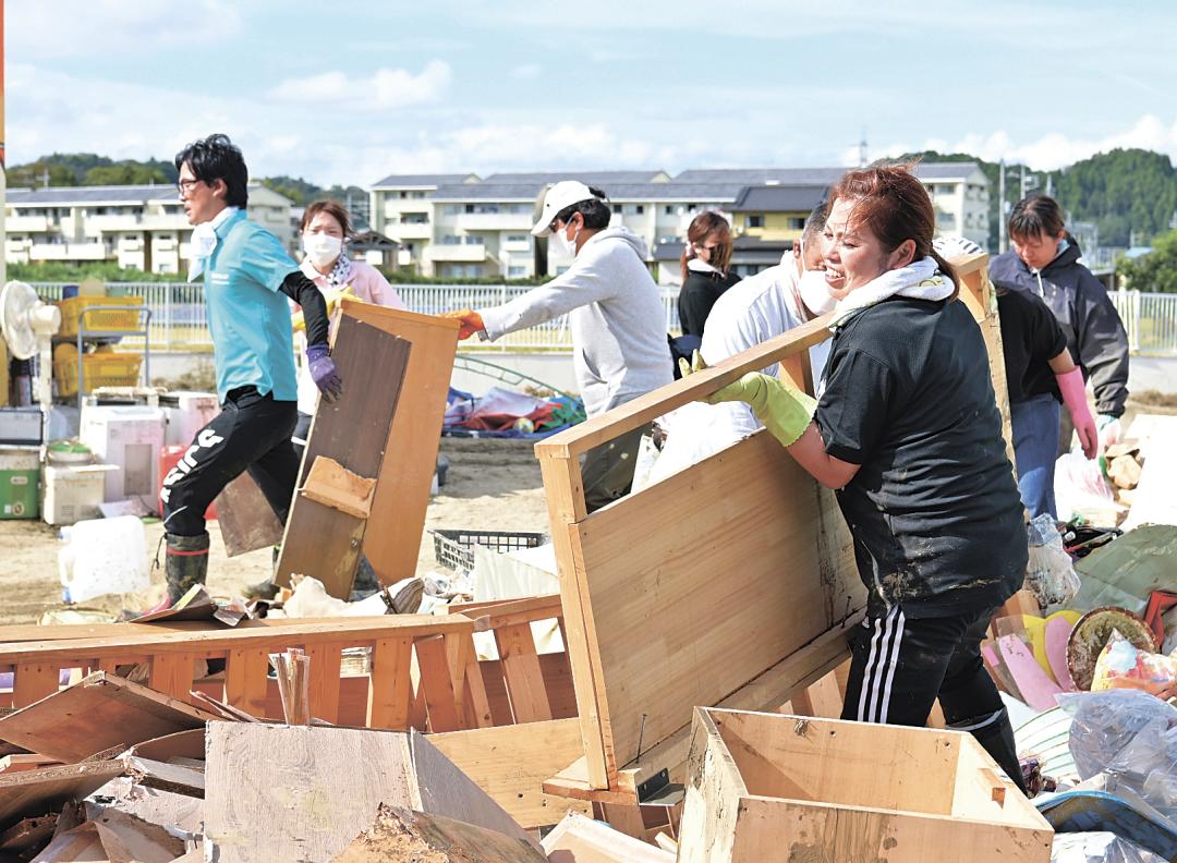 浸水した棚などを園庭に運び出す誠之会幼稚園の職員ら=北茨城市関南町関本下