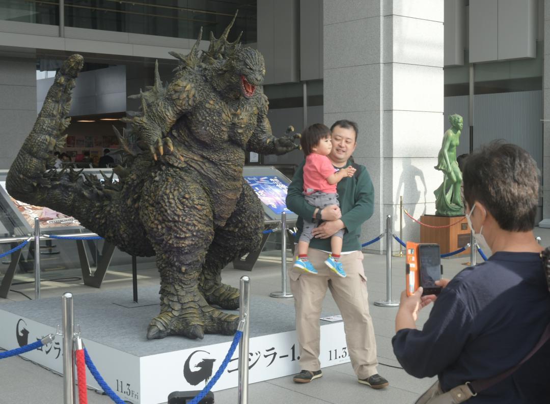 県庁入り口に展示されたゴジラの立像を撮影する来場者=水戸市笠原町
