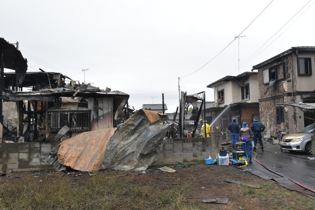 ７棟が焼けた住宅火災の現場を調べる捜査員と鎮火に当たる消防職員ら＝２６日午前１１時１５分ごろ、土浦市並木