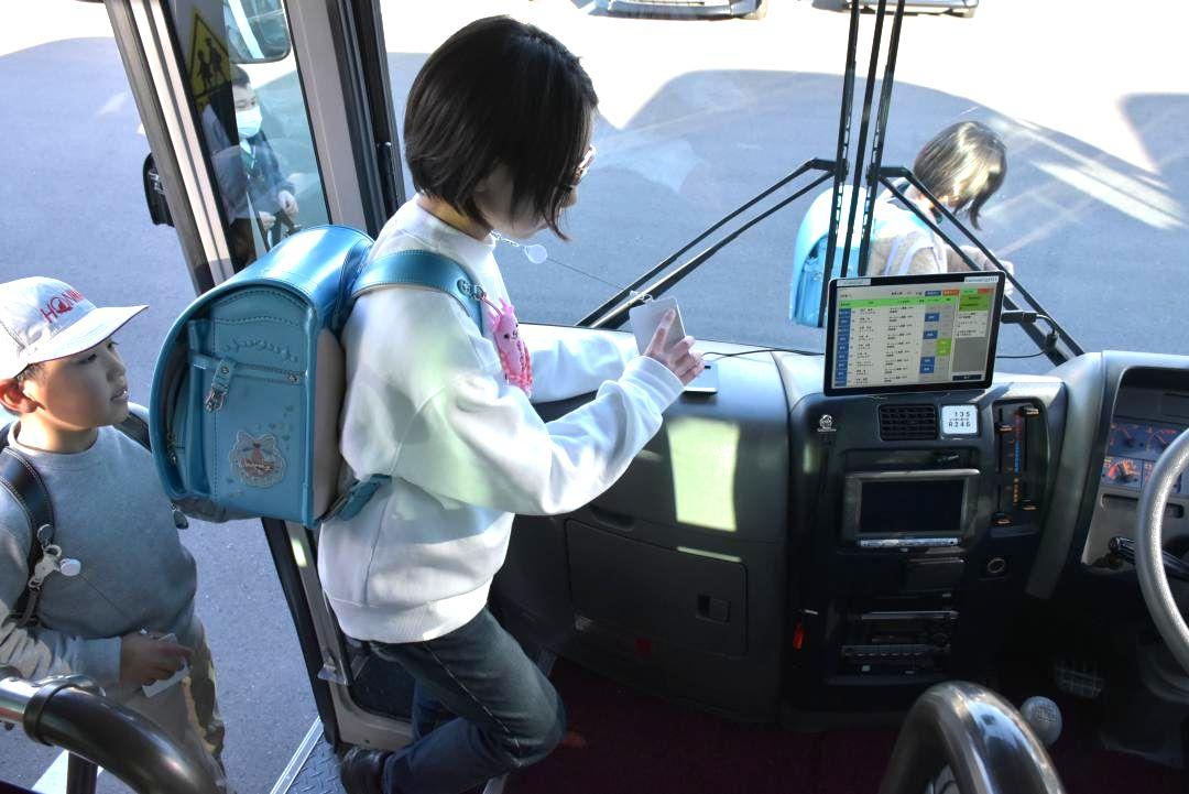 読み取り機にICカードをかざしてスクールバスに乗車する児童=かすみがうら市上佐谷の市立千代田義務教育学校
