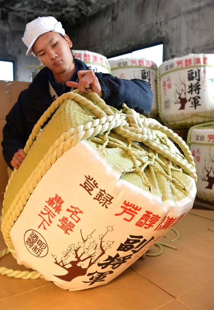 縄で締め上げ飾り樽を作る従業員=水戸市元吉田町
