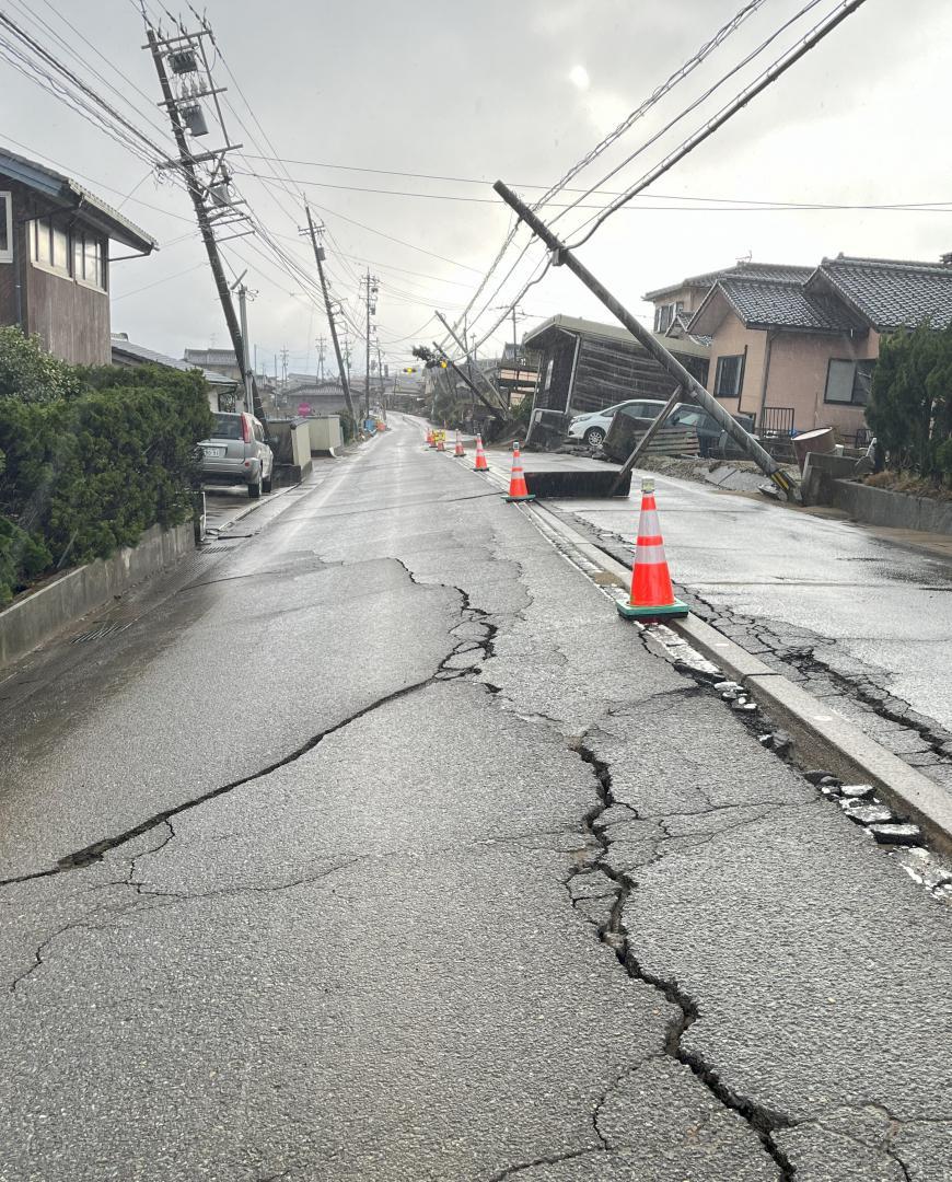 液状化でひび割れた道路と傾いた電柱=石川県内灘町(先名氏提供)
