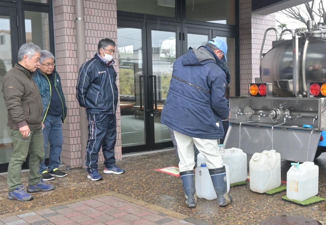 給水車からポリ容器に水をくむ住民たち=大洗町磯浜町