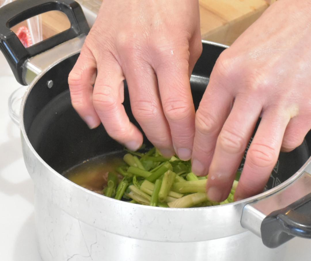 炊飯鍋にコメや調味料などを入れ、最後にセリの茎を入れる
