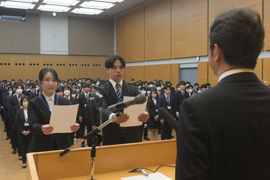 県の入庁式で宣誓する新採職員代表の塚田芽久さん(左)と鮏川友一さん(中央)=県庁
