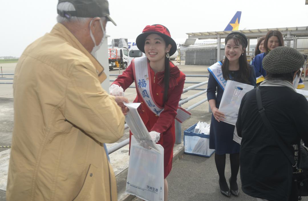 就航10周年を迎えた福岡便の利用者に記念品を配る福岡観光大使の山口愛華さん(左から2人目)ら空港関係者=小美玉市与沢
