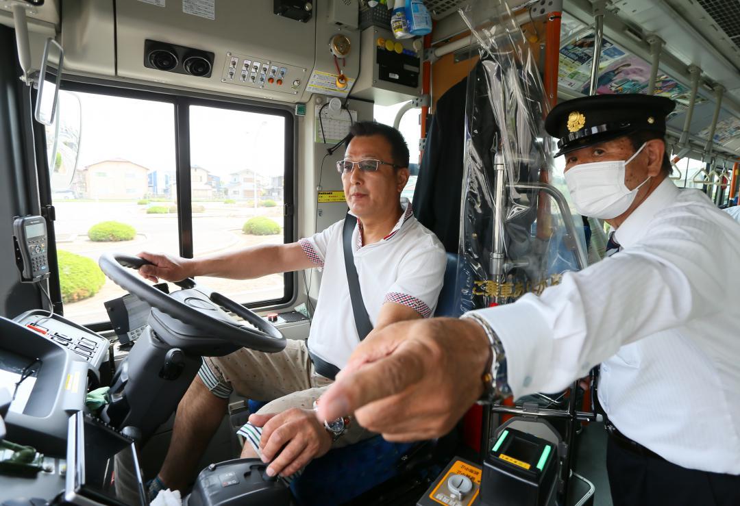 自動車教習所のコースでバスの運転体験をする参加者(中央)=那珂市菅谷
