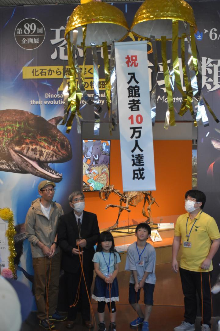 くす玉を割り、企画展の入館者10万人達成を祝う石和大誠君(右から2人目)=坂東市大崎
