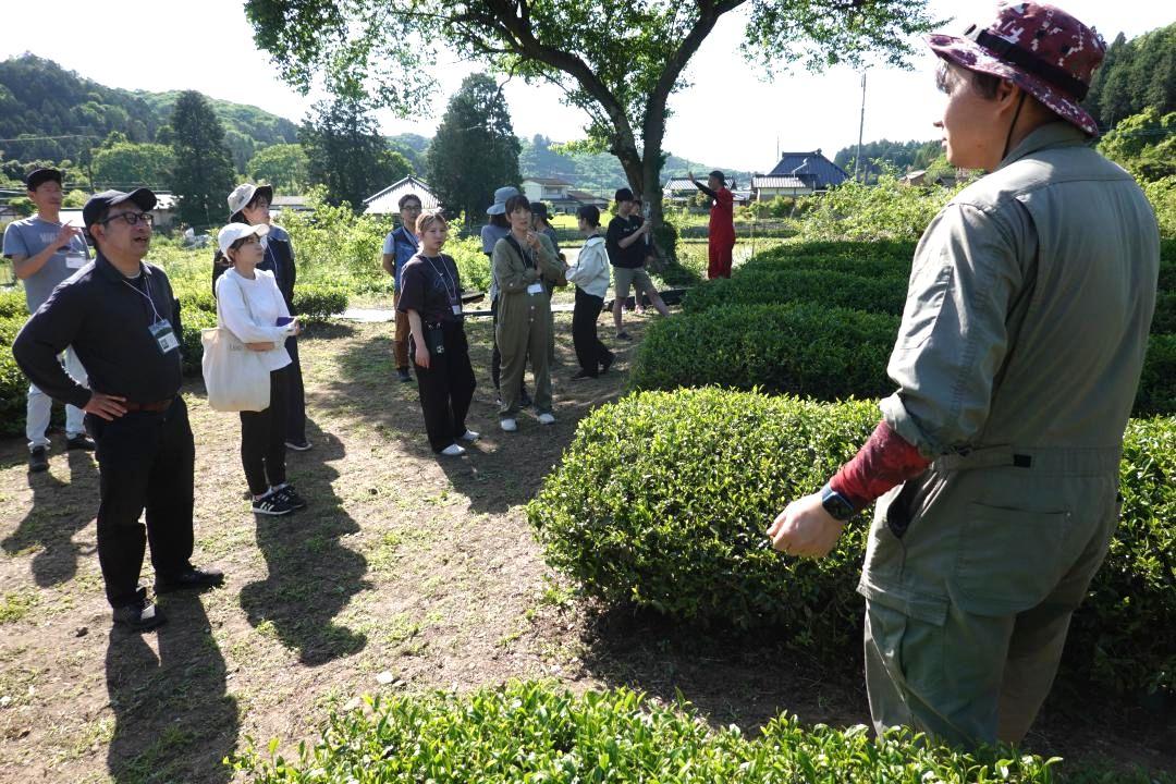 町に定住し就農した元地域おこし協力隊員(右)の話に耳を傾けるバスツアーの参加者たち=城里町上古内
