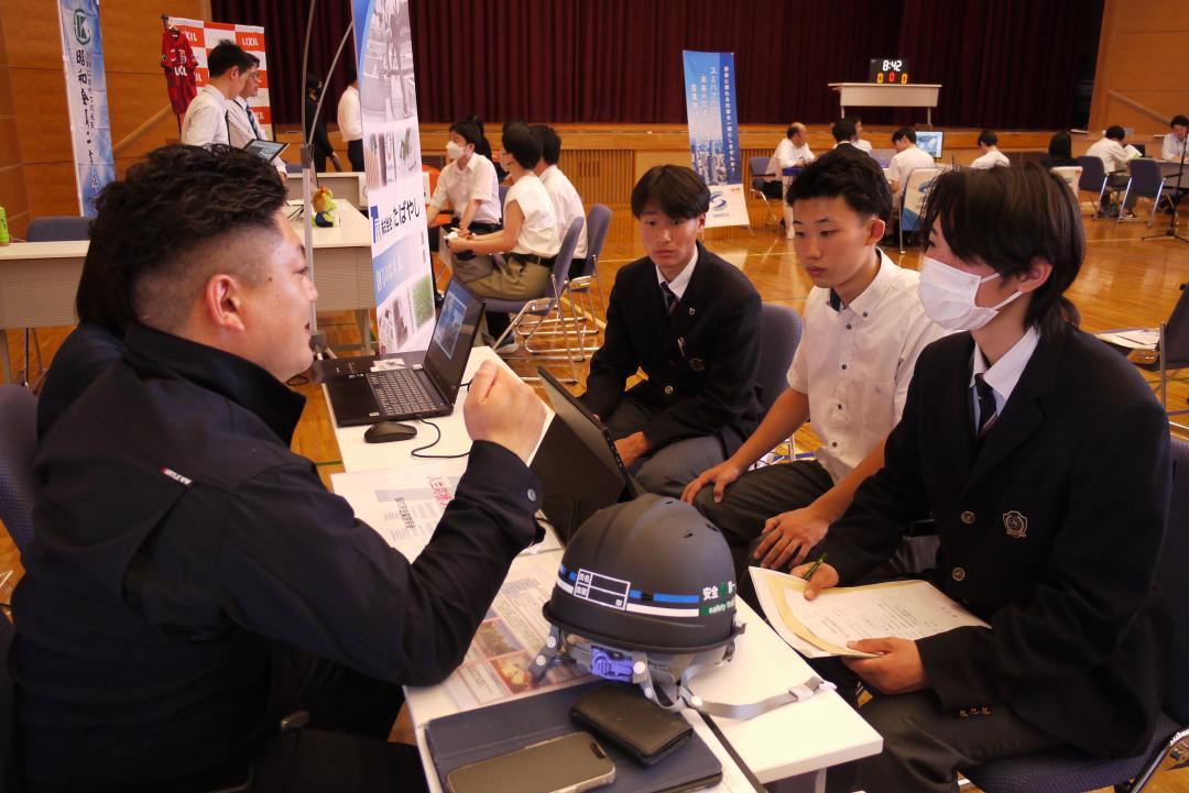 出展企業の担当者(左)から説明を受ける高校生たち=桜川市羽田
