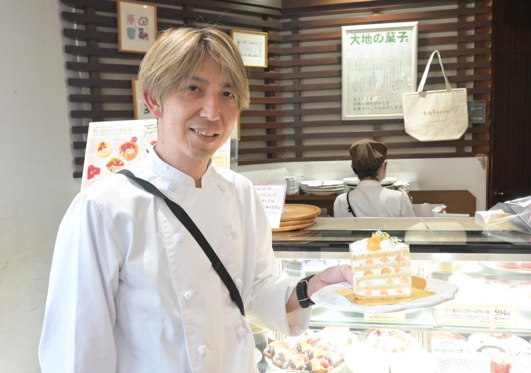 なだろうレッドを使用したケーキを持つラ・テールの栗原清商品開発部長=東京都内
