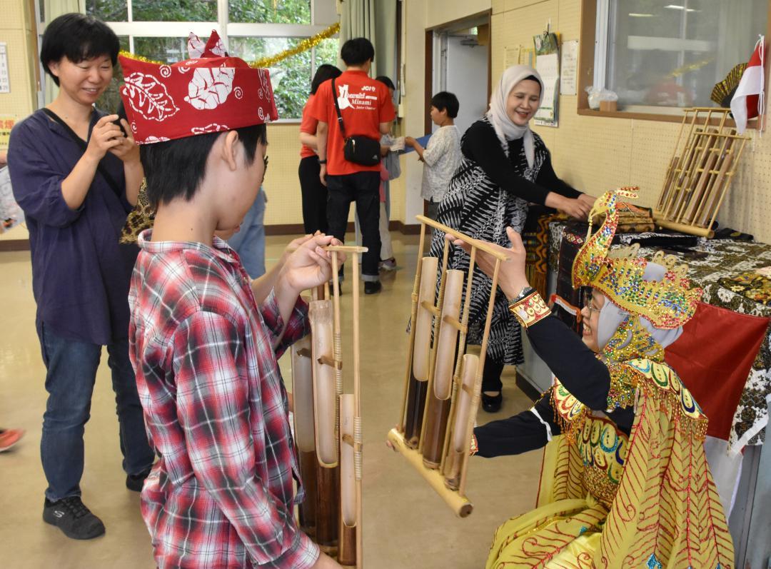 インドネシアの竹製楽器「アンクルン」の説明を受ける参加者ら=守谷市板戸井
