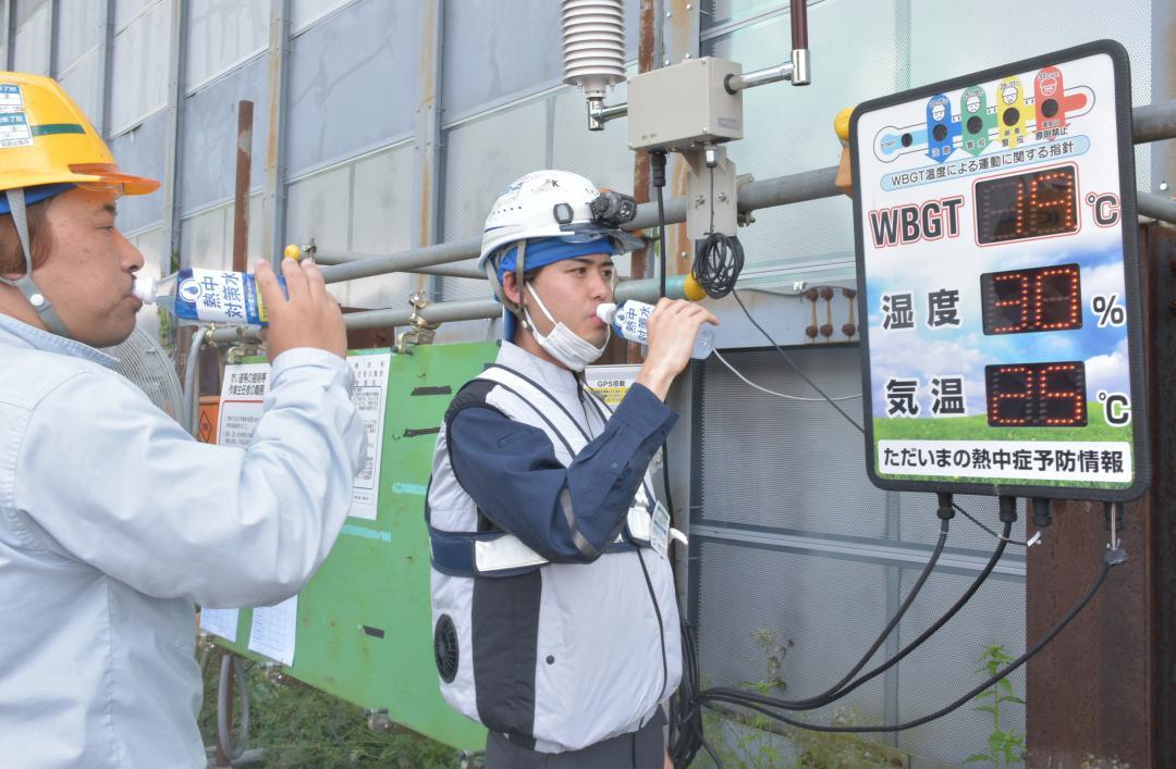 暑さ指数(WBGT)を確認しながら水分補給する作業員=茨城町常井
