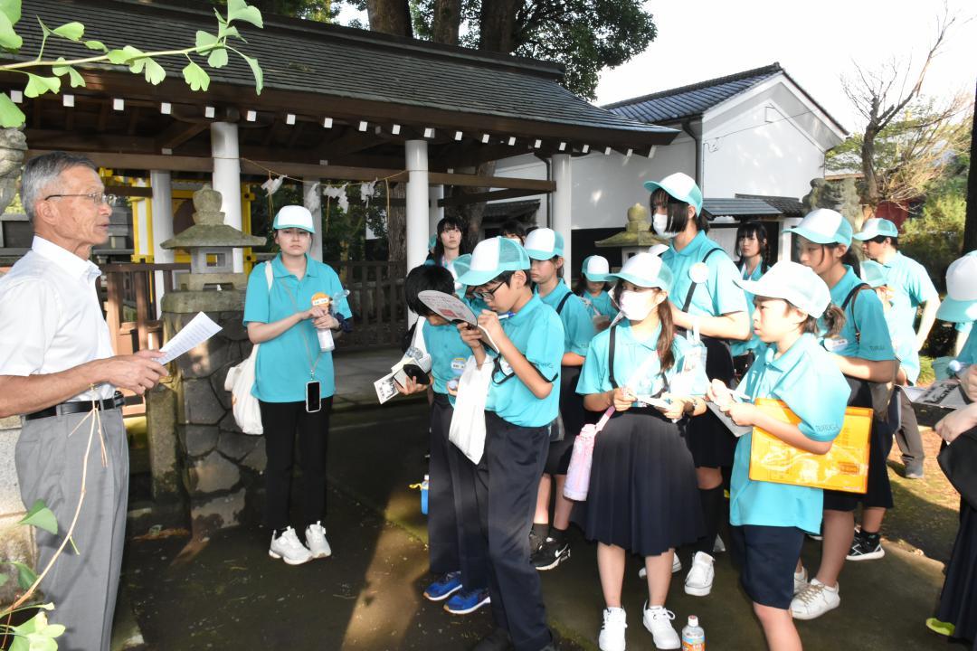 回天神社代表役員の羽部道紀さん(左)の説明に聞き入る福井県敦賀市の児童ら=水戸市松本町
