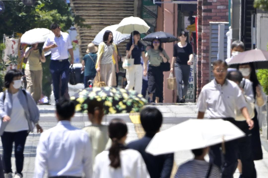 暑さでかげろうが立つ街中を歩く人たち=22日午後0時22分、水戸市南町