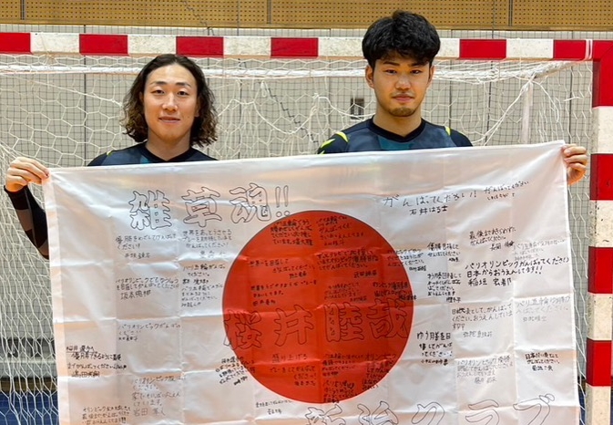 応援メッセージの入った国旗を掲げる元木博紀選手(左)と桜井睦哉選手(かすみがうら市提供)
