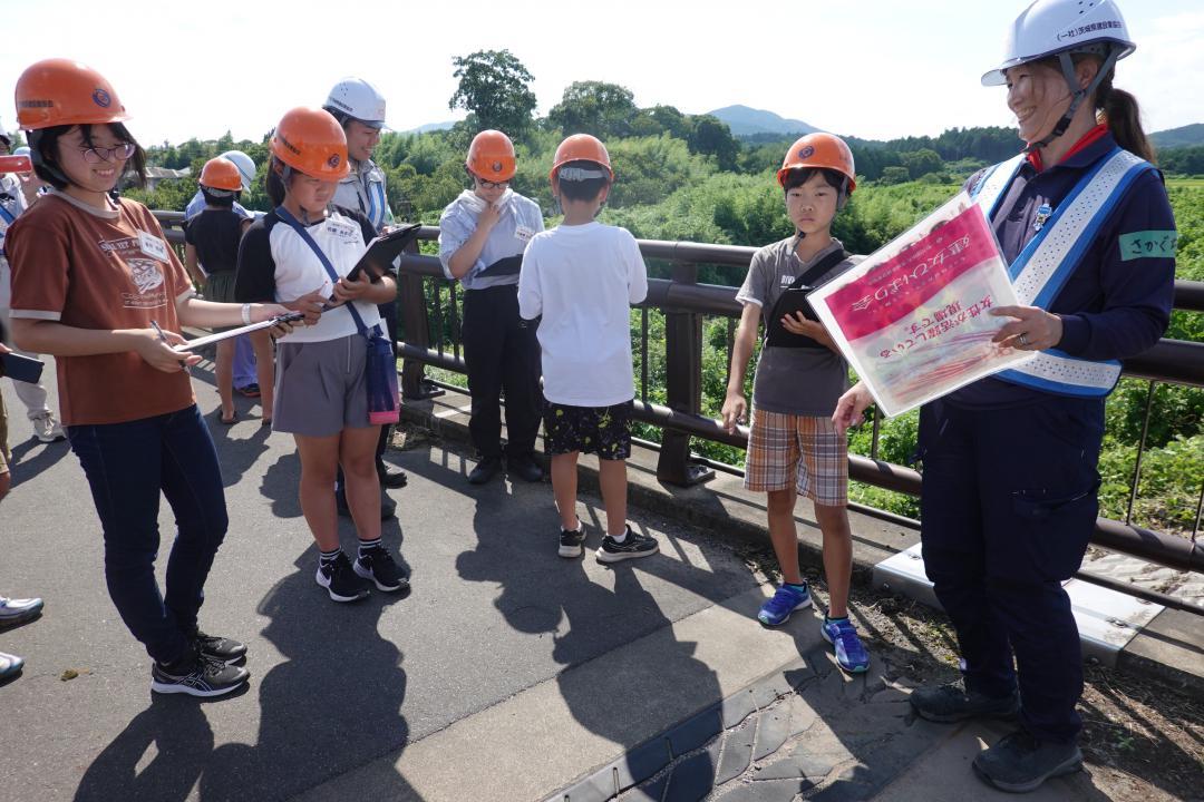 女性土木技術者(右)の案内で橋の点検を体験する小中学生の参加者ら=笠間市矢野下付近
