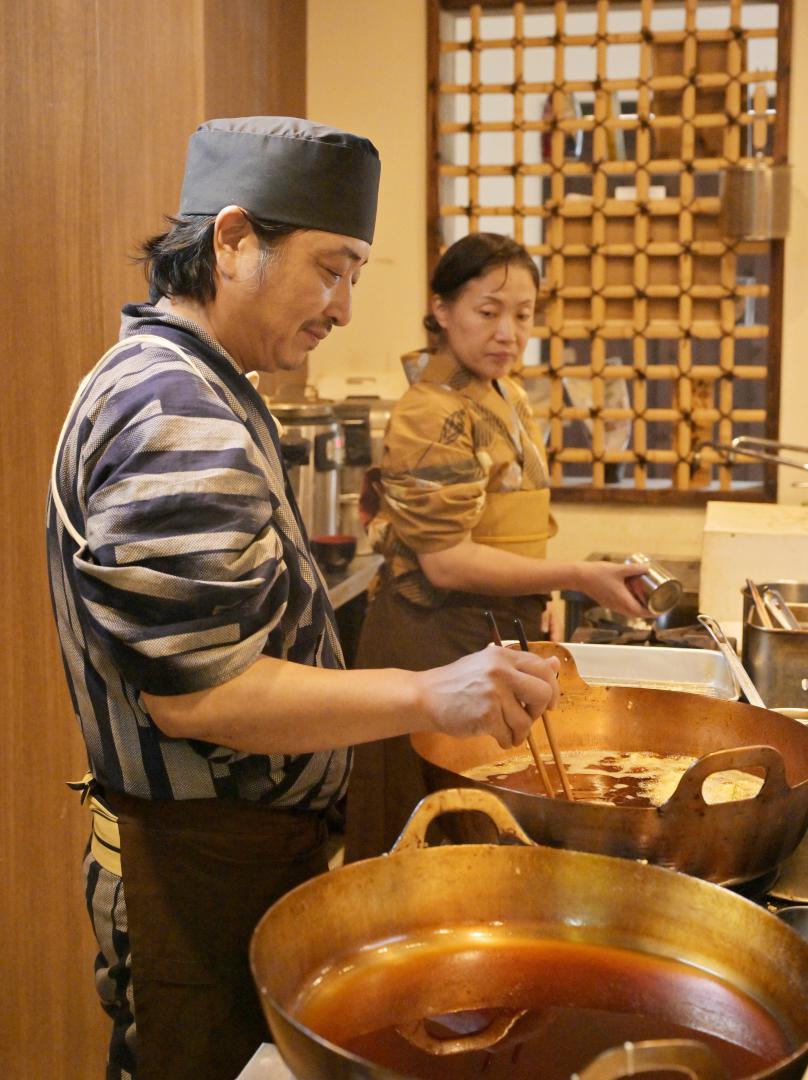 天ぷらを揚げる「みそら亭」の店主・岩楯博史さん(手前)と妻の早苗さん=日立市若葉町
