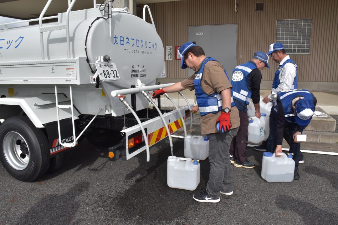 民間の給水タンク車からポリタンクに給水する給水ボランティア=常陸太田市内田町
