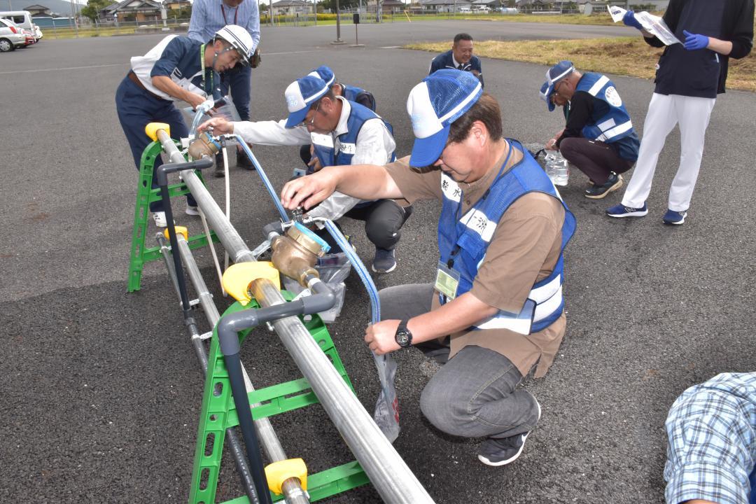 仮設給水栓から市の非常用飲料水袋などへ給水する給水ボランティア=常陸太田市内田町
