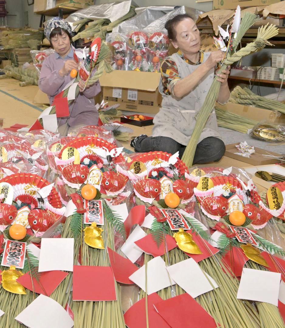 紅白の扇など縁起物をしめ縄に飾り付ける女性ら=常陸太田市大中町、高松美鈴撮影
