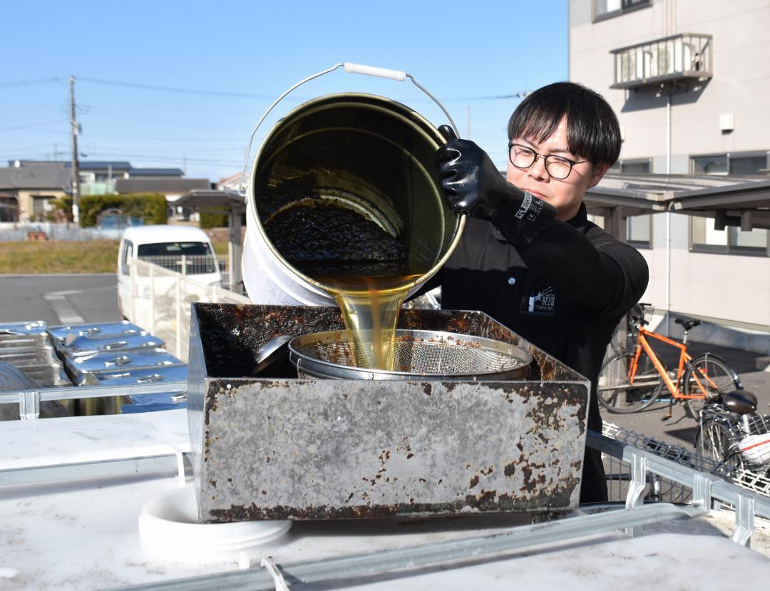 鹿島アントラーズFCのアカデミーハウスから廃食用油を回収するレボインターナショナル社員=鹿嶋市平井東
