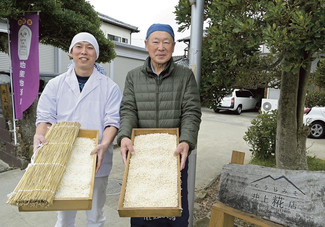 麹蓋の糀を見せる6代目井上一彦さん(右)と息子の祐也さん。祐也さんが手にするのは調湿に重要な菰=つくば市北条
