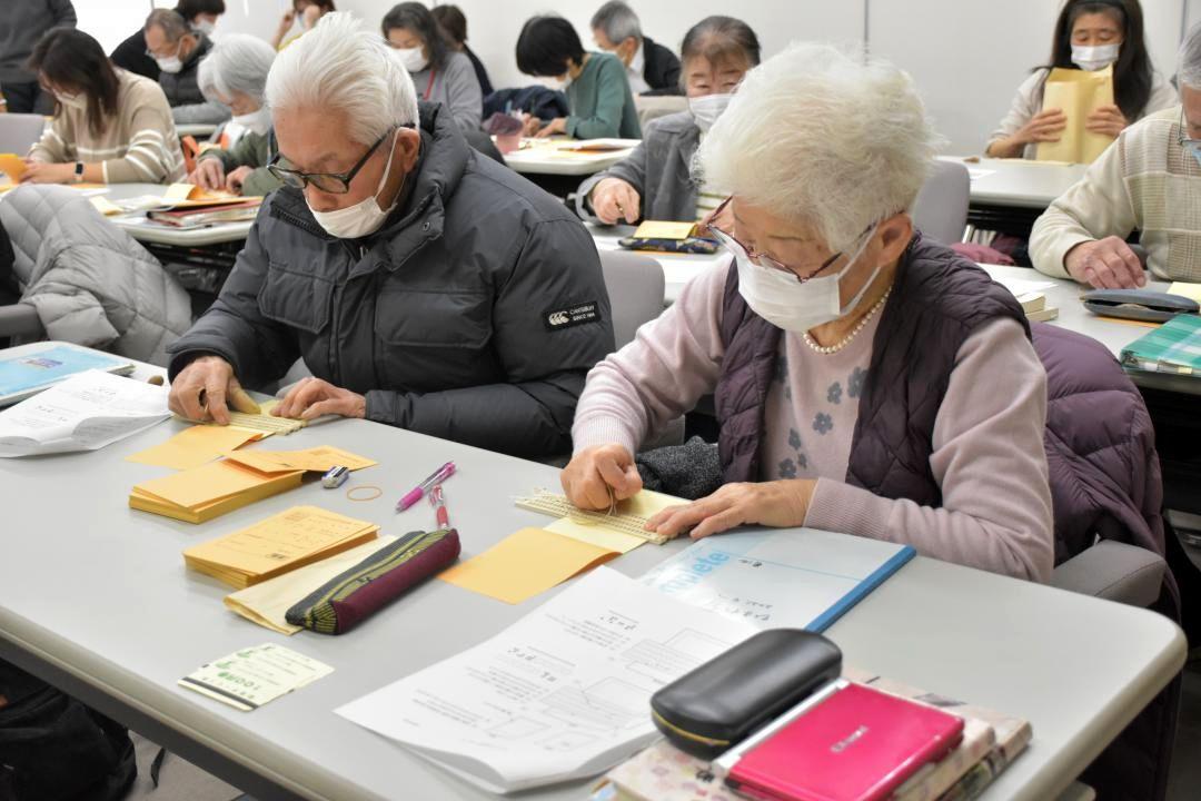 点字器で丁寧に打ち込む土浦市のボランティア団体「ひまわりの会」のメンバーら=土浦市大和町
