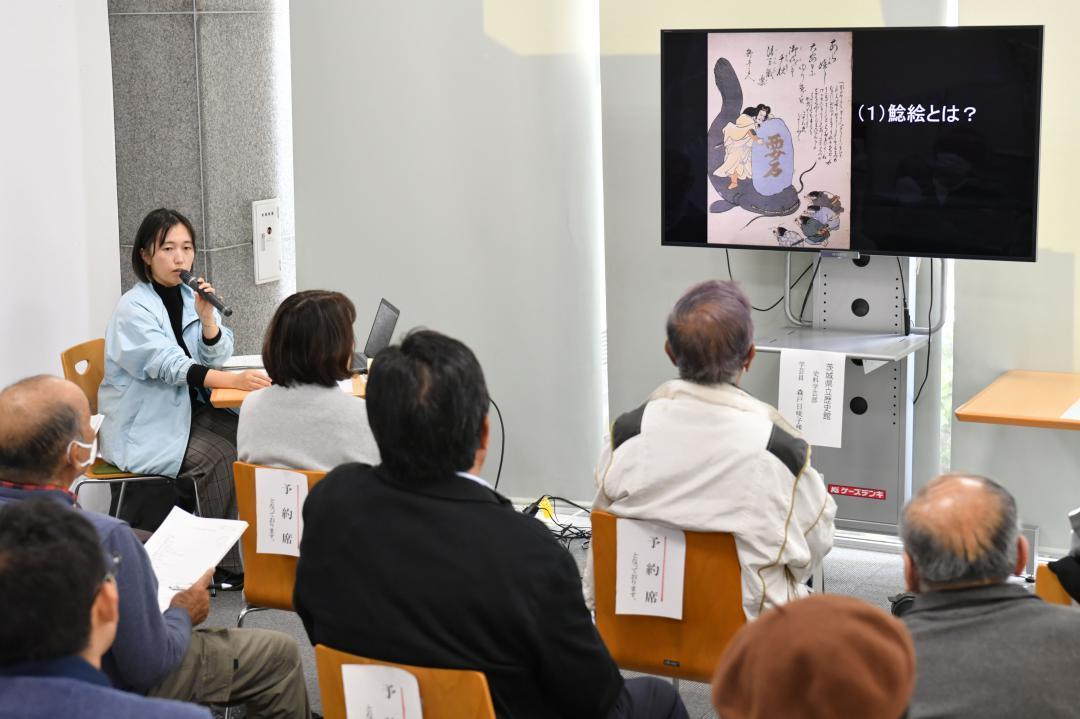 鯰絵について解説する県立歴史館の森戸日咲子学芸員(左)=水戸市南町