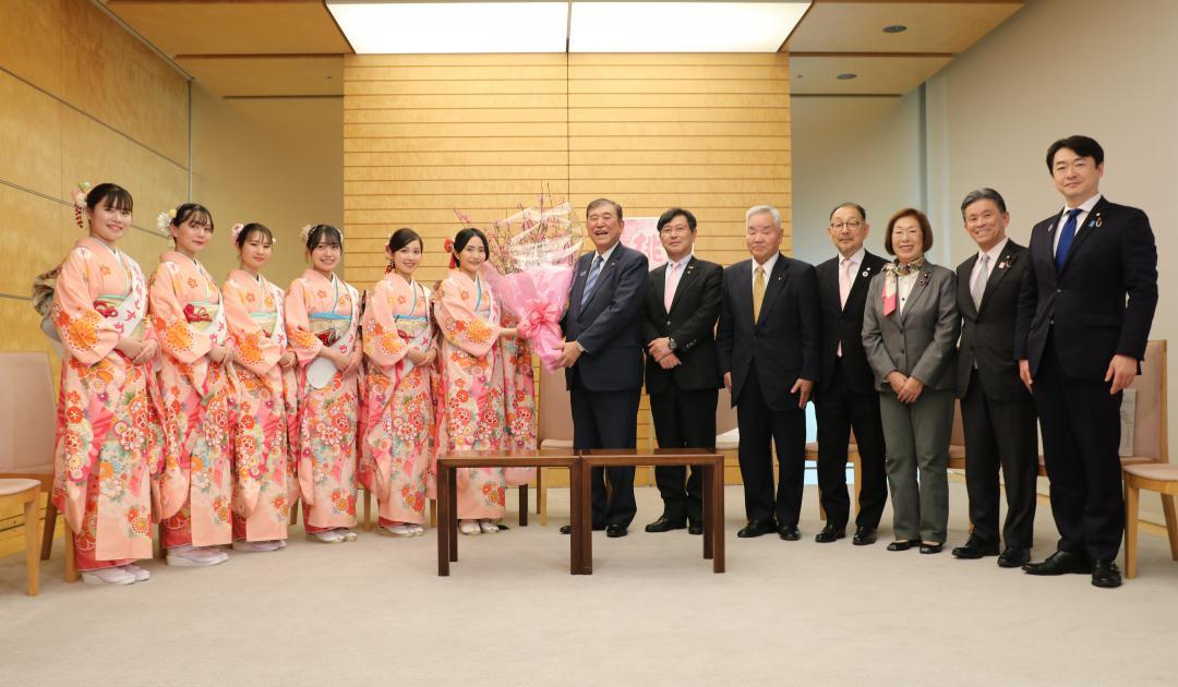 観光大使「古河桃むすめ」から桃の花を受け取る石破茂首相(中央)=首相官邸(永岡桂子衆議院議員事務所提供)
