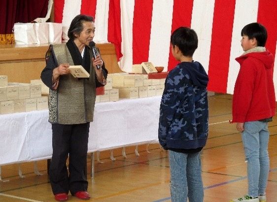 七面焼の茶わんを児童らに手渡す伊藤瓢堂さん(左)=水戸市浜田(2019年、水戸市立浜田小提供)
