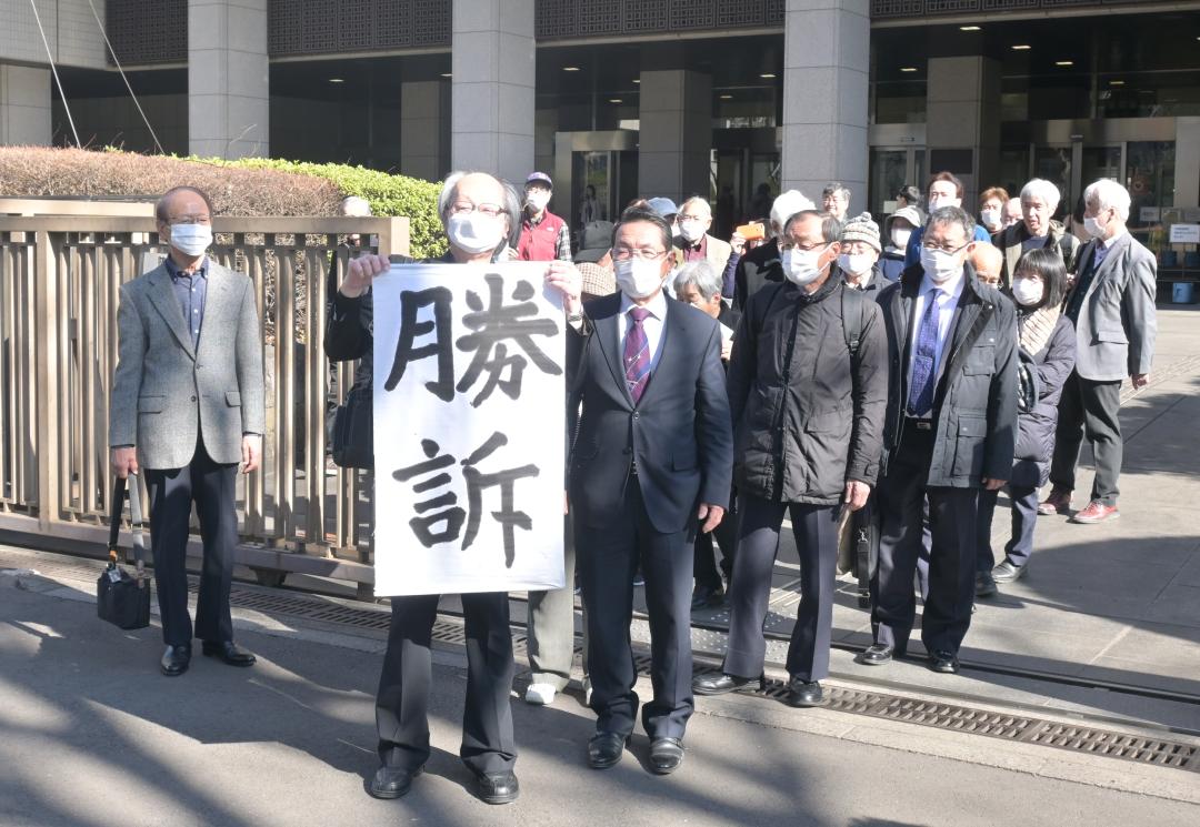 常総水害訴訟の控訴審判決後、「勝訴」と書かれた旗出しを行う原告団ら=26日午後2時8分ごろ、東京都千代田区の東京高裁前