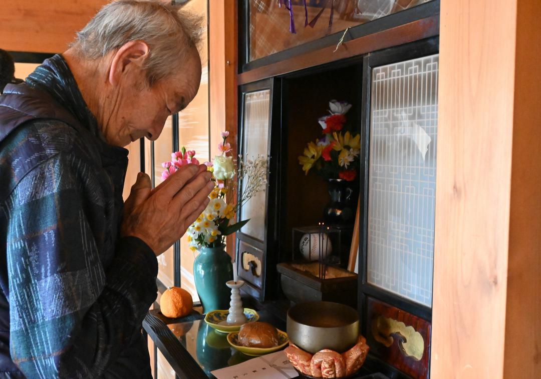 兄の平塚幸男さんをしのんで仏壇に手を合わせる信次さん=北茨城市磯原町豊田
