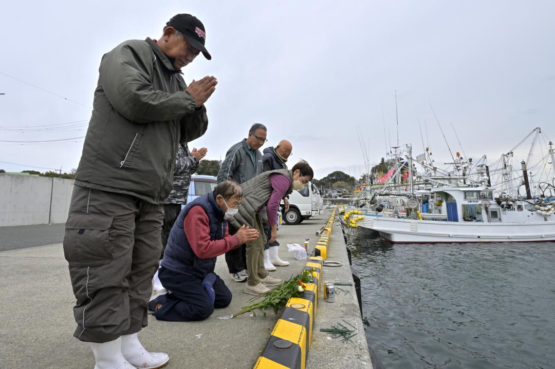 東日本大震災で行方不明となった漁師仲間を思い、手を合わせる人たち=11日午後1時57分、北茨城市大津町