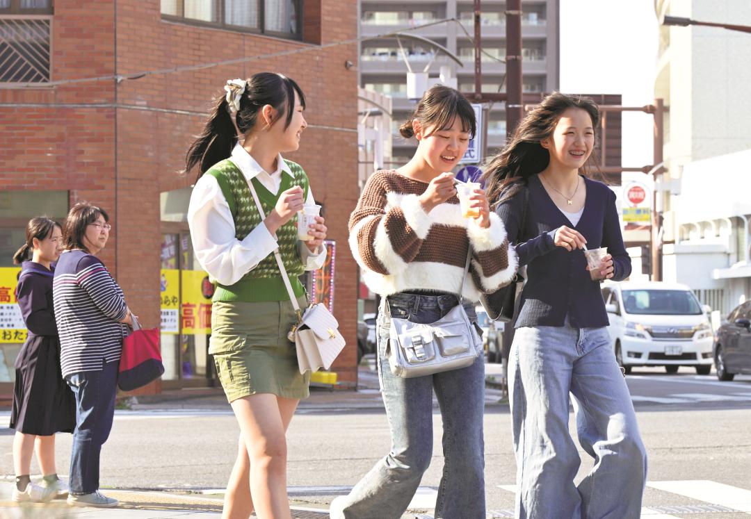 気温が上昇し、アイスを食べながら歩く人たち=23日午後2時50分ごろ、土浦市大和町